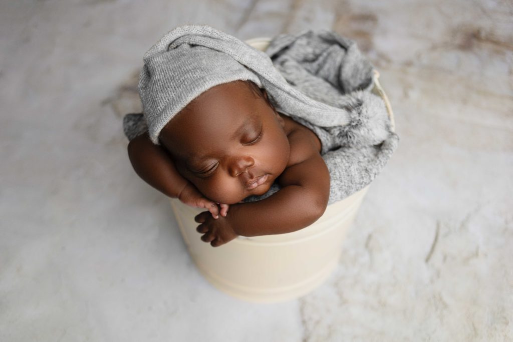 newborn baby boy in grey hat posed in bucket