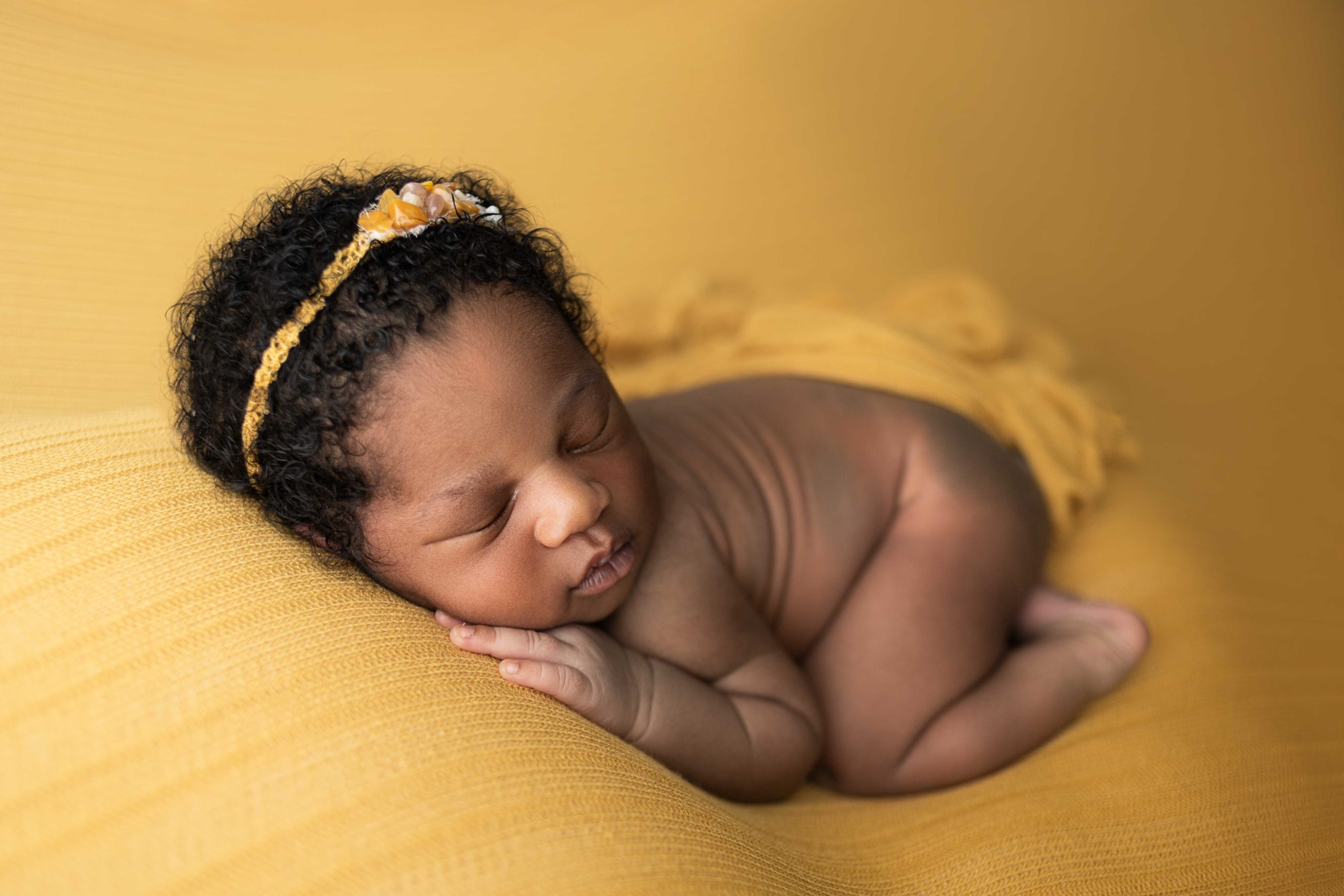 newborn baby girl in bum up pose on mustard yellow backdrop